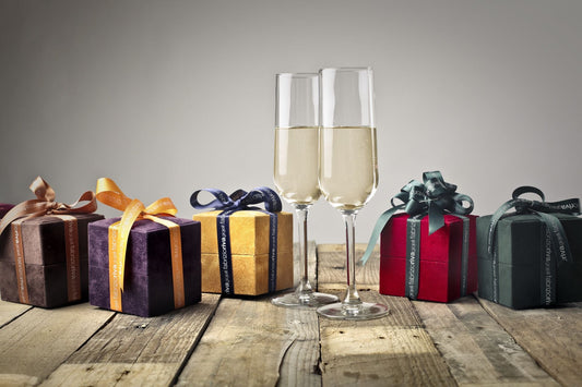 Wrapped gift boxes beside two glasses on a celebration table — wine lover gifts for every occasion