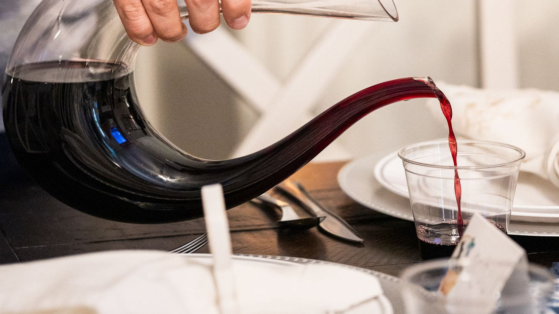 Pouring red wine from an elegant decanter at a dining table — the barware that sets a scene