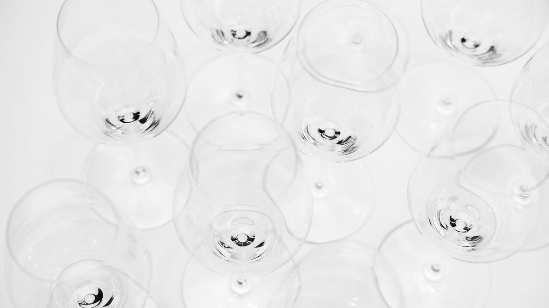 Overhead view of empty wine glasses of different shapes arranged on a white surface