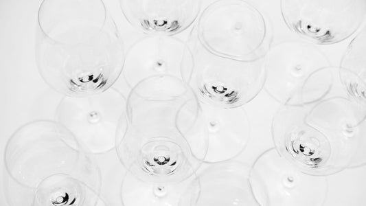 Overhead view of empty wine glasses of different shapes arranged on a white surface