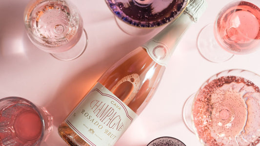 Flat lay of a rose bottle and assorted wine glasses on a soft pink surface