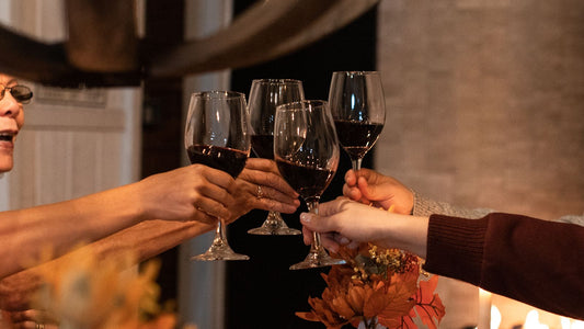 Friends raising glasses of red wine in a toast at a warm dinner gathering