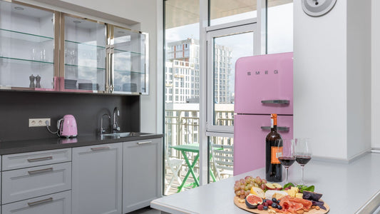 A bottle of red wine, two glasses and a fruit platter on the table of a bright new kitchen