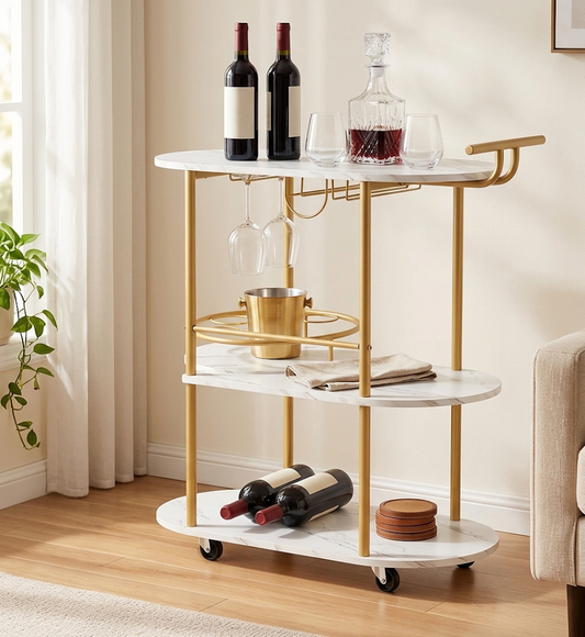 Gold three-tier bar cart with white marble-look shelves, styled with red wine bottles, a crystal decanter, hanging stemware and a gold ice bucket